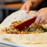 Pancheros employee using Bob to mix ingredients for a burrito